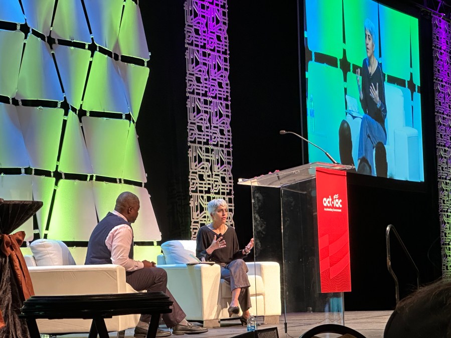 OPM Director Kiran Ahuja sits on stage at ACT-IAC's Imagine Nation ELC23 event. She is speaking to Melivn Brown, OPM's deputy chief information officer.