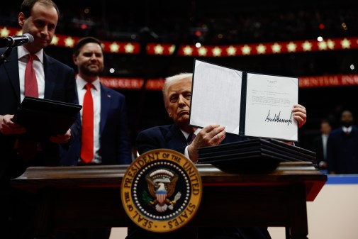 President Donald Trump holds up an executive order after signing it during an indoor inauguration parade at Capital One Arena on Jan. 20, 2025.