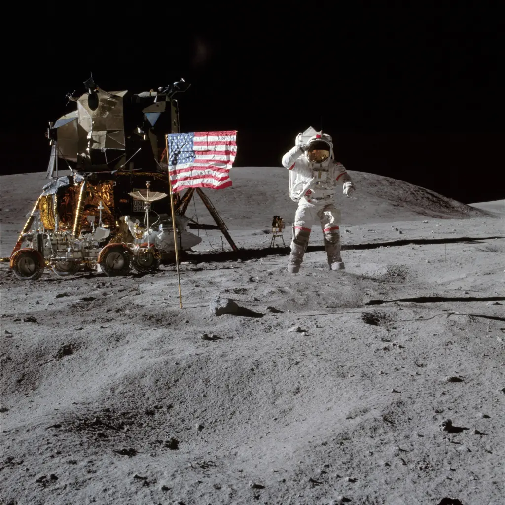 The photo shows Young jumping next to an American flag and saluting. The flag hangs eerily taught, signifying the low-gravity environment on the Moon. The lunar module "Orion" is in the background of the photo.
