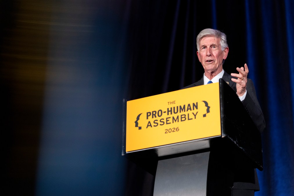 Beyer speaks from behind a lectern with a yellow sign on it that reads "Pro-Human Assembly 2026."