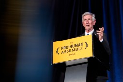 Beyer speaks from behind a lectern with a yellow sign on it that reads "Pro-Human Assembly 2026."