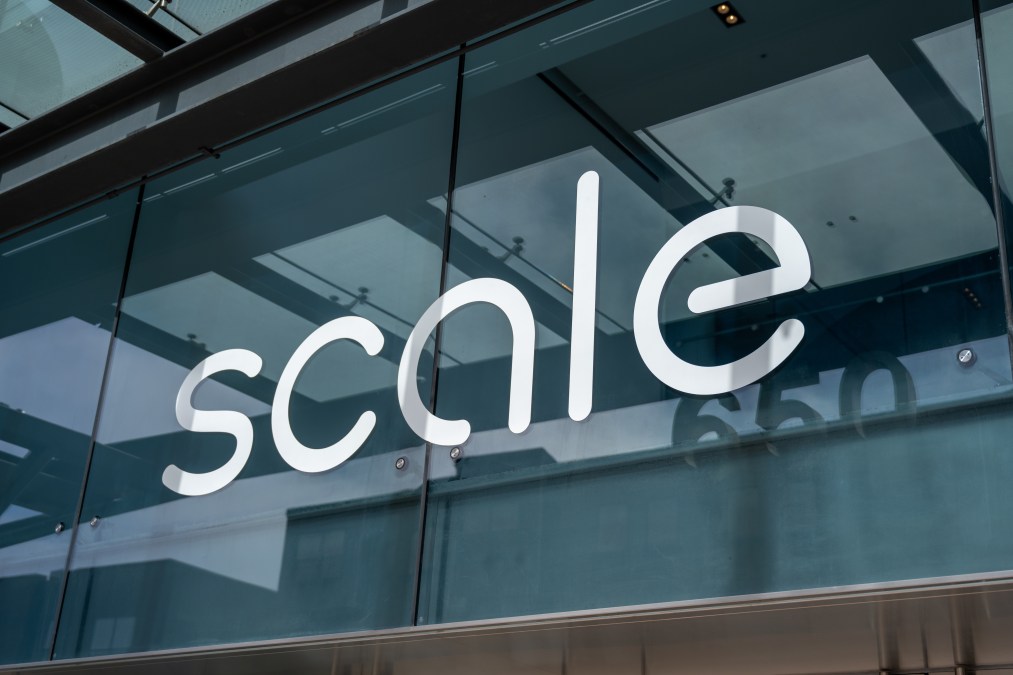 The Scale logo is seen on the outside of a building. The camera shot is up close. The Scale logo is the company's name in white lowercase letters.
