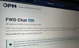 The photo shows photo of Federal Workforce Data Chat (FWD Chat) open on a computer screen. The banner across the top has the OPM logo and below that, the page reads "FWD Chat Beta."